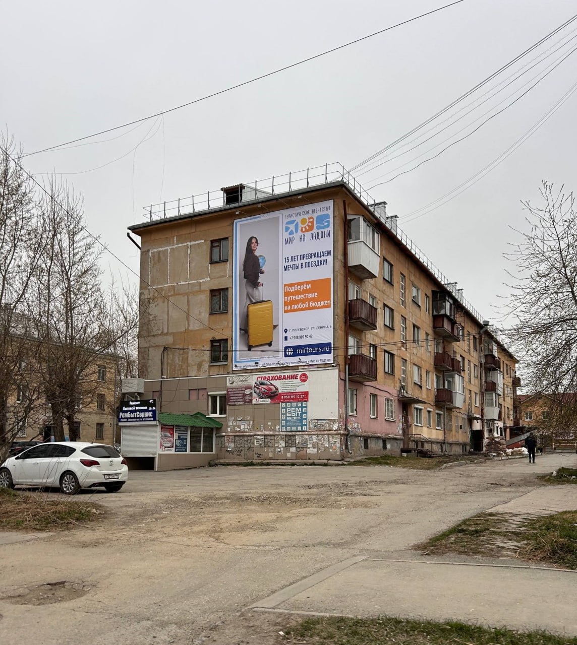 Брандмауэр на торце жилого дома с юбилейным макетом турагентства «Мир на ладони»