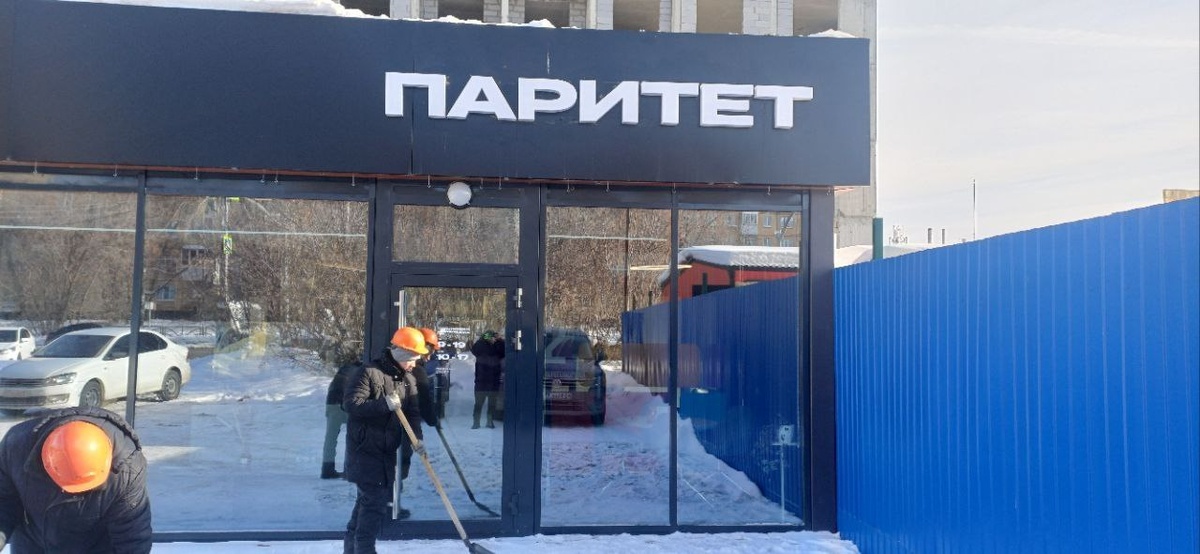 Объёмные белые буквы «ПАРИТЕТ» на тёмном фасаде офиса продаж застройщика